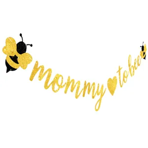 Detailed shot of gold glitter bee mommy to bee banner, baby shower party decoration closeup.