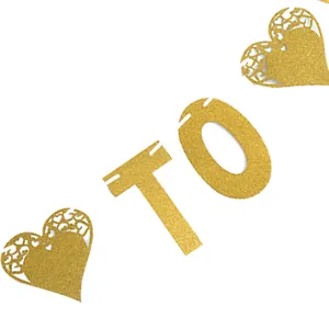 Detalle de letra TO en papel con purpurina dorada y corazon para decoracion de pancarta.