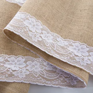 Detailed close-up of natural burlap table runner with elegant white floral lace trim design.
