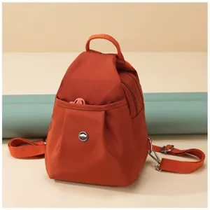 Detailed view of the mini orange casual backpack featuring durable fabric, front pocket and straps.