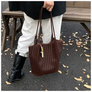 Detail view of dark brown woven leather tote bag street style outfit with fine straps and charm