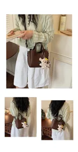 Minimalist brown leather tote bag detail showing fine texture, stitching and cute bear charm.