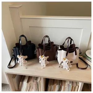 Detailed view of stylish minimalist handbags with cute knitted charms displayed on wooden shelf.