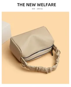 Detail view of retro beige pillow shoulder bag with pleated handle and double zippers.
