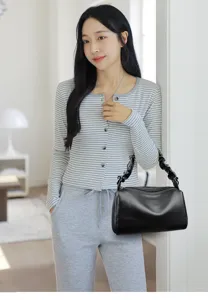 Detail shot of a chic black leather pillow bag with gathered handle, shown in stylish indoor setting.