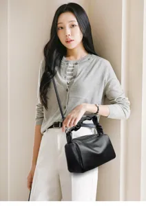 Close-up detail of the black leather ruched handle pillow bag worn by model in daily outfit.