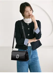 Detail view of the elegant black leather shoulder bag with chic silver rectangular metal buckle.