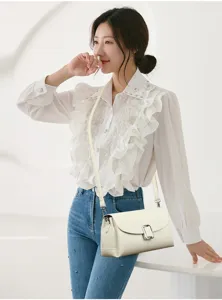 Close-up detail of a minimalist women's white leather crossbody bag in use.