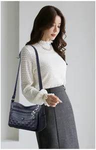 Λεπτομερής άποψη της μαλακής δερμάτινης καπιτονέ τσάντας χιαστί με πολλαπλές θήκες φερμουάρ.