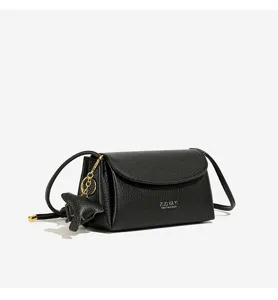 Classic minimalist black leather crossbody bag with flap and chic metal pendant detail.