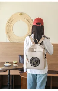 Detail view of a stylish beige casual backpack featuring an embroidered elephant pattern.
