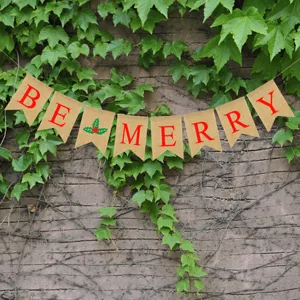 Close-up detail of rustic burlap Christmas banner hanging on green ivy wall, holiday decor.