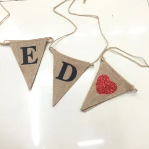 Detailopname van jute vlaggenwimpels met gedrukte letters en rood hart voor feest.