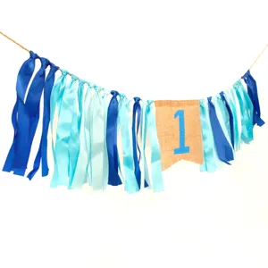 Detail view of 1st birthday high chair banner with blue ribbons and burlap number one flag.