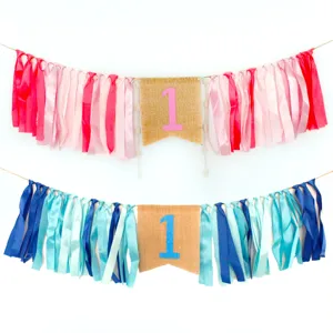 Detailed close-up view of the first birthday high chair banner featuring pink and blue ribbon tassels.