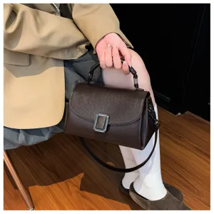 Close-up detail of retro brown textured shoulder bag with chic metal buckle design.