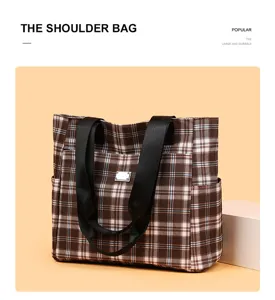 Detailed view of the brown plaid canvas tote bag with black webbing handles and metal buckle.