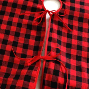 Nahaufnahme des rot-schwarzen Karo-Christbaumrocks mit festlichen Schleifenbändern.