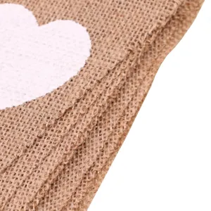 Primo piano di tessuto di juta naturale con stampa a cuore bianco per decorazioni rustiche.