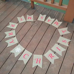 Christmas burlap banner detail showing red printed letters and snowflake on wooden background.