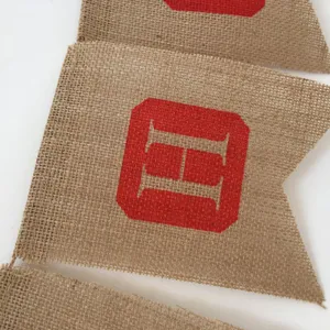 Close-up of burlap Christmas party bunting flag featuring a red printed geometric emblem design.