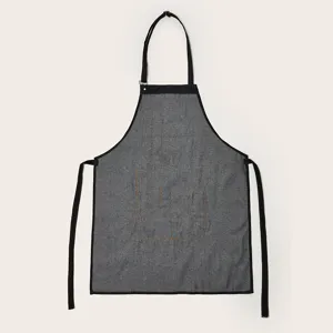 Close-up detail of the dark gray washed denim apron featuring contrast stitching and pockets.