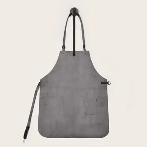 Detailed view of grey leather work apron with brown straps and functional pocket design.