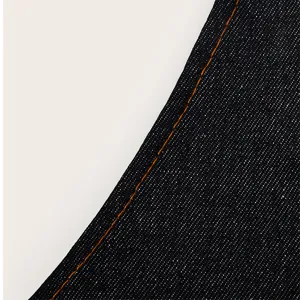 Detailed view of dark blue denim fabric texture with classic orange contrast stitching.