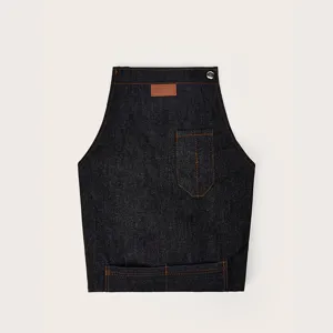 Dark denim apron detail shot featuring contrast orange stitching and pocket design.
