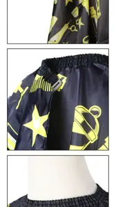 Black haircut cape with yellow scissors pattern detail shot, professional salon apron.