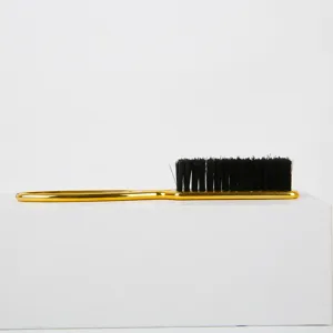 Cepillo para el pelo con mango dorado y cerdas negras para peinado profesional diario.