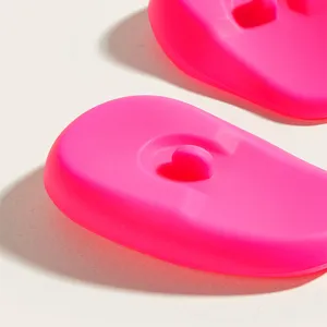 Silicone hair dye ear covers close-up view, bright pink protective ear caps for salon styling.