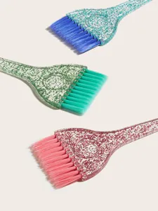 Gros plan sur des pinceaux de coloration avec manches pailletés transparents et poils souples.