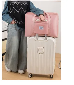 Grand sac de voyage pliable rose avec poche zippée pour fixation sur valise à roulettes.