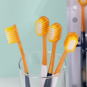 Gros plan de brosses à dents pour adultes à tête large et poils souples dans un verre, hygiène