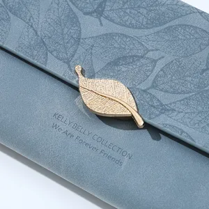 Close-up detail of blue faux leather long wallet with elegant gold leaf clasp and texture.