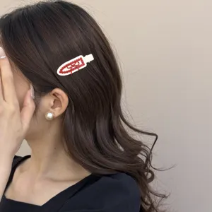 Gedetailleerde close-up van een Koreaanse wit-rode strik haarspeld in golvend haar.