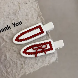 Detailopname van witte haarspelden met rode geschulpte rand en strik, stijlvol accessoires