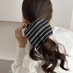 Detail shot of chic black and white striped hair scrunchie worn on low ponytail, elegant style.