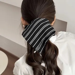 Detail view of black and white striped fabric hair scrunchie, stylish low ponytail accessory.
