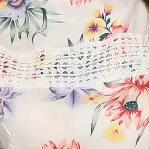 Close-up detail of women summer floral printed dress with white crochet lace panel trim.