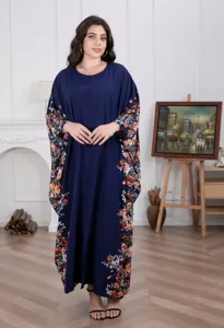 Detailed view of women's loose long caftan dress, dark blue fabric with colorful floral print.