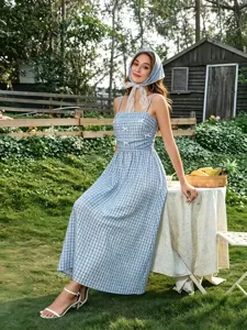 Scène de jardin montrant les détails de la robe à bretelles à carreaux bleus et style.