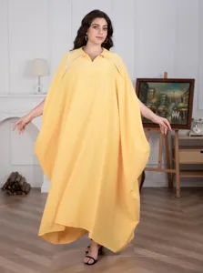 Gedetailleerd aanzicht van de gele oversized kaftan jurk met vleermuismouwen en strass kraag.