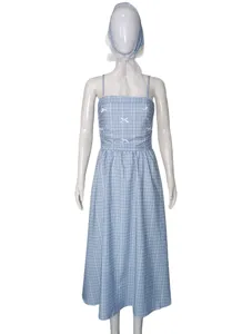Détail de robe à bretelles à carreaux bleus avec nœuds délicats et foulard en dentelle.