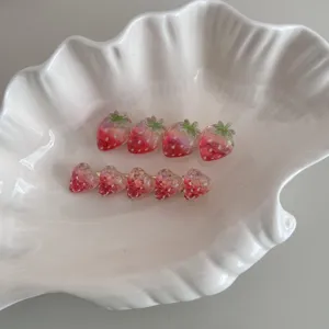 Gros plan de pinces à cheveux fraise en résine mignonne dans un plat en céramique.