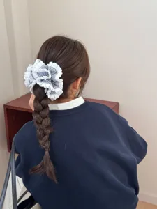 Close-up detail van blauw-wit gestreepte haarscrunchie met volants in gevlochten haar.
