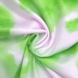 Close-up view of vibrant green and white tie-dye fabric texture with soft elastic drape.