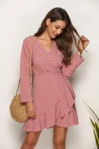 Detailed view of women's pink polka dot ruffle wrap dress with long sleeves in casual lifestyle scene.