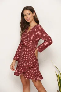 Detail close-up of a stylish burgundy polka dot long sleeve wrap dress with a chic ruffle hem.